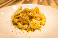Mac & Cheese Close-up of Mac & Cheese with creamy sauce and golden herb breadcrumb topping on a white plate