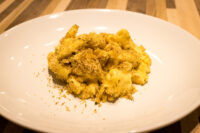 Mac & Cheese White plate of Mac & Cheese with creamy pasta and a golden breadcrumb topping.