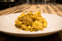 Mac & Cheese Plate of Mac & Cheese topped with golden herb breadcrumbs, set on a wooden table.