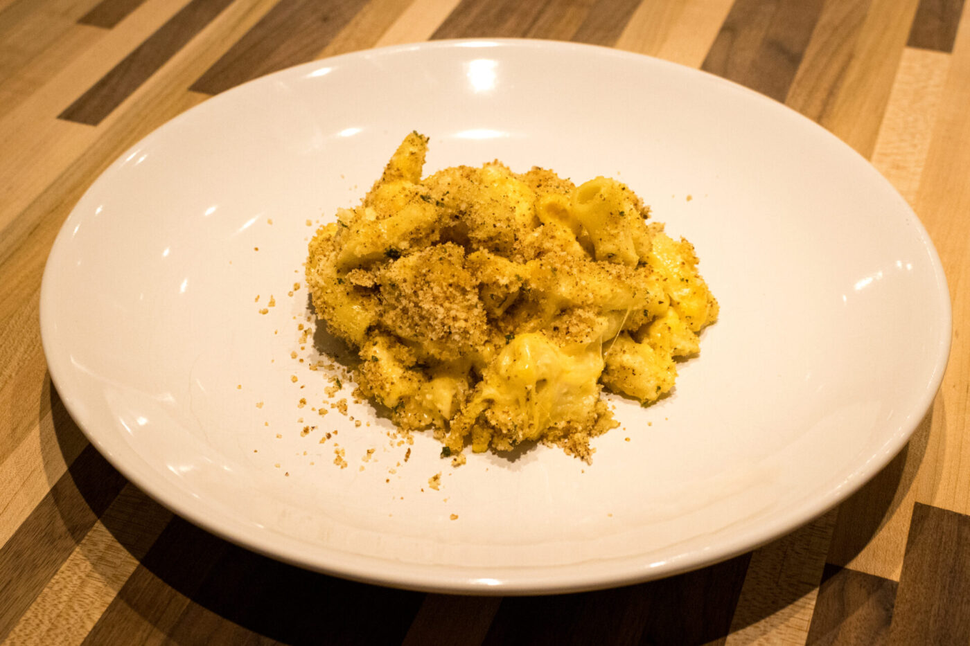 Mac & Cheese A plate of Mac & Cheese with creamy pasta topped in golden herb breadcrumbs.