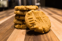 Peanut Butter Cookies Stack of Peanut Butter Cookies with crosshatch fork marks, one leaning cookie in front on wood