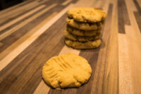 Peanut Butter Cookies Stack of Peanut Butter Cookies with crosshatch fork marks, one cookie set apart on a striped wooden table.