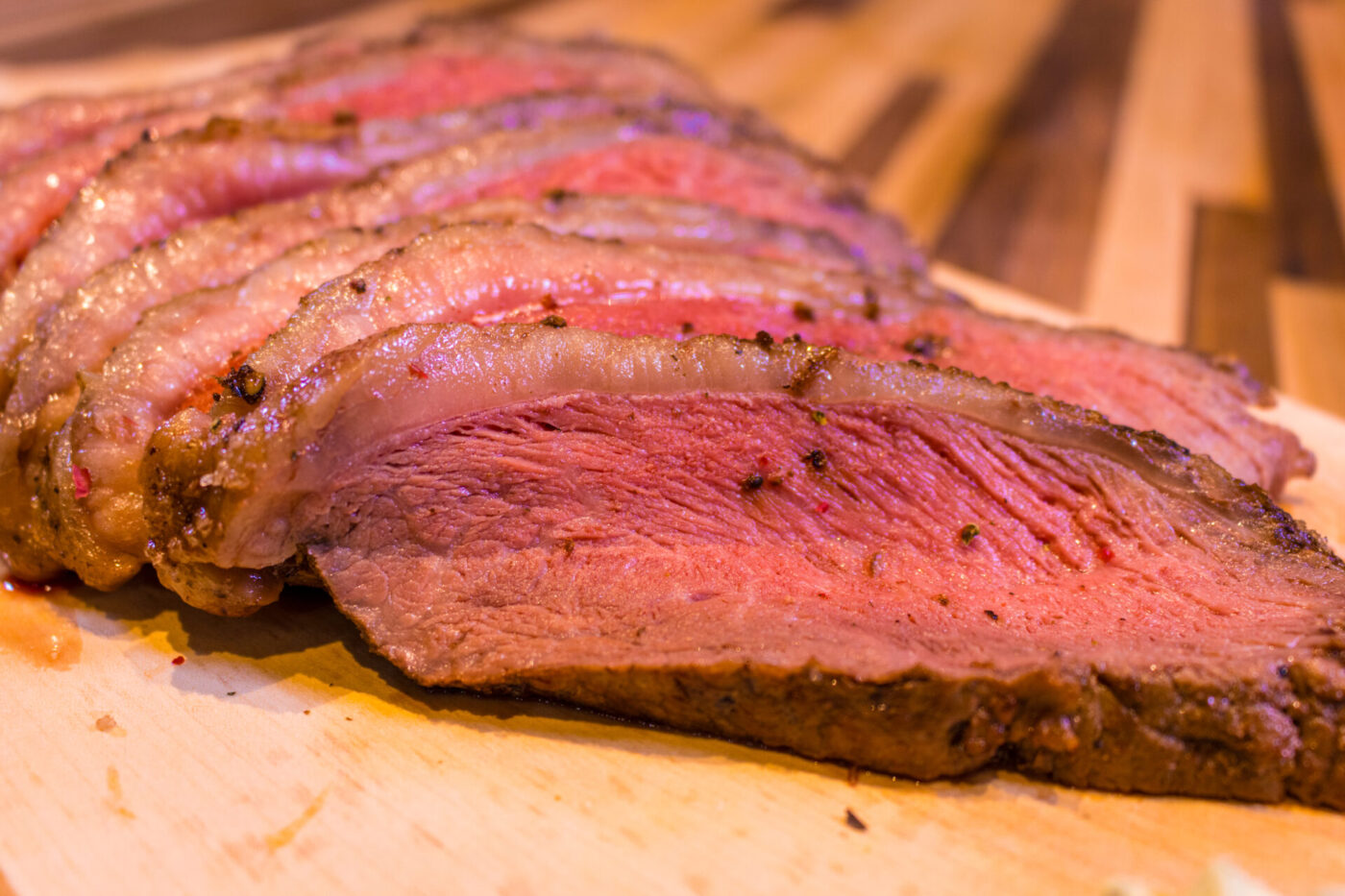Beef Picanha in Salt Crust Sliced Beef Picanha in Salt Crust, showing pink medium-rare interior and dark seasoned crust on a wooden board