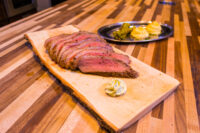 Beef Picanha in Salt Crust Sliced Beef Picanha fanned on a wooden board with a herb butter dollop, mashed potato and greens plated behind