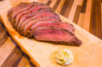 Beef Picanha in Salt Crust Sliced Beef Picanha in Salt Crust fanned on a wooden board with a swirl of herb butter