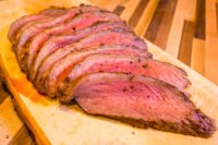 Beef Picanha in Salt Crust Sliced Beef Picanha in Salt Crust fanned on a wooden board, pink center and dark crusted edge.