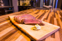 Beef Picanha in Salt Crust Sliced Beef Picanha in Salt Crust fanned on a wooden board with a dollop of herb butter.