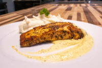 Salmon in Mustard Sauce Seared Salmon in Mustard Sauce fillet on mashed potatoes with creamy sauce and parsley garnish.