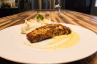 Salmon in Mustard Sauce Seared Salmon in Mustard Sauce fillet with pale sauce swirl, mashed potato, and herb garnish on a white plate.