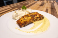 Salmon in Mustard Sauce Seared Salmon in Mustard Sauce fillet on a pool of cream sauce, beside swirled mashed potatoes.