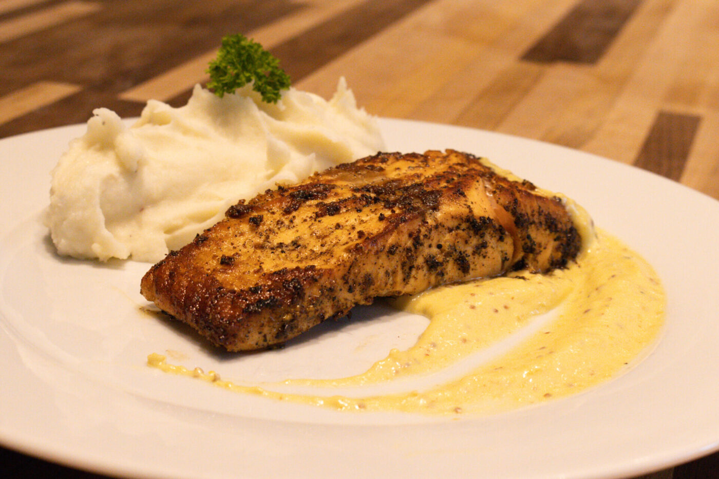 Salmon in Mustard Sauce Seared Salmon in Mustard Sauce fillet with mashed potatoes and pale cream sauce on a white plate