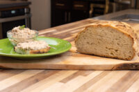 Sardines Dip or Spread Bowl of Sardines Dip or Spread with herb garnish and a topped bread slice on a green plate beside a sliced loaf.