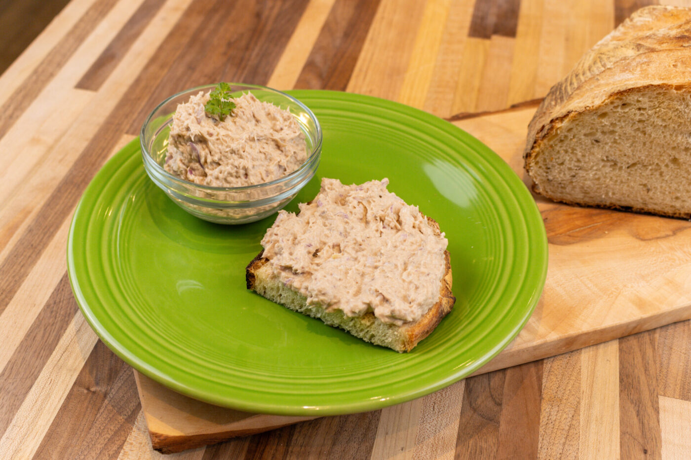 Sardines Dip or Spread Glass bowl of Sardines Dip or Spread beside a slice of bread spread with it on a green plate.