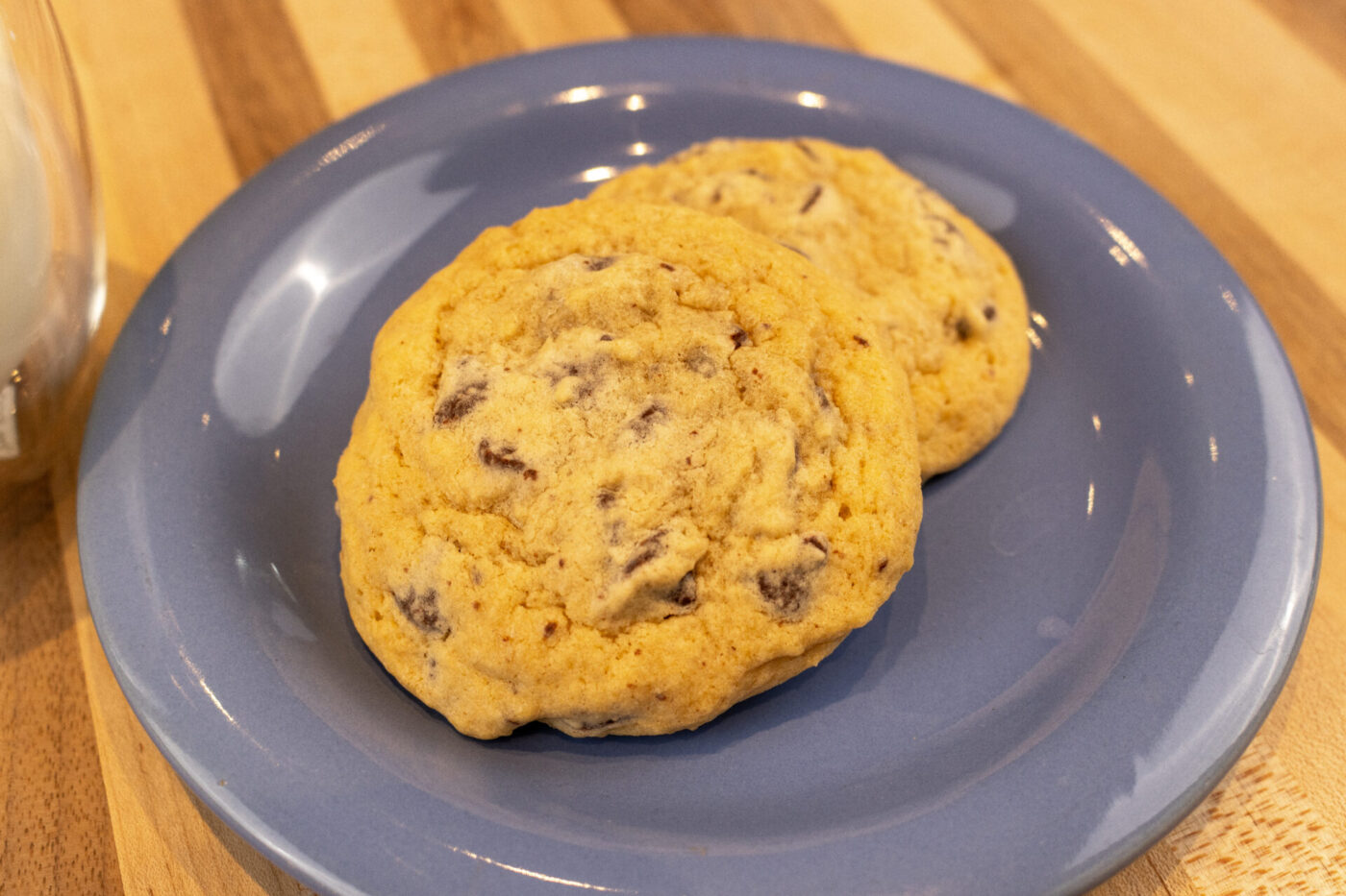 Chocolate Chip Cookies Two Chocolate Chip Cookies stacked on a blue plate atop a wooden table.