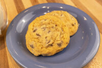 Chocolate Chip Cookies Two Chocolate Chip Cookies stacked on a blue plate atop a wooden table.