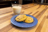 Chocolate Chip Cookies Two Chocolate Chip Cookies on a blue plate beside a glass of milk on a wooden table