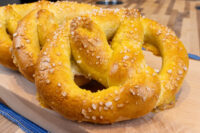 Golden-brown Czech Soft Pretzel Preclík topped with coarse salt on a wooden board
