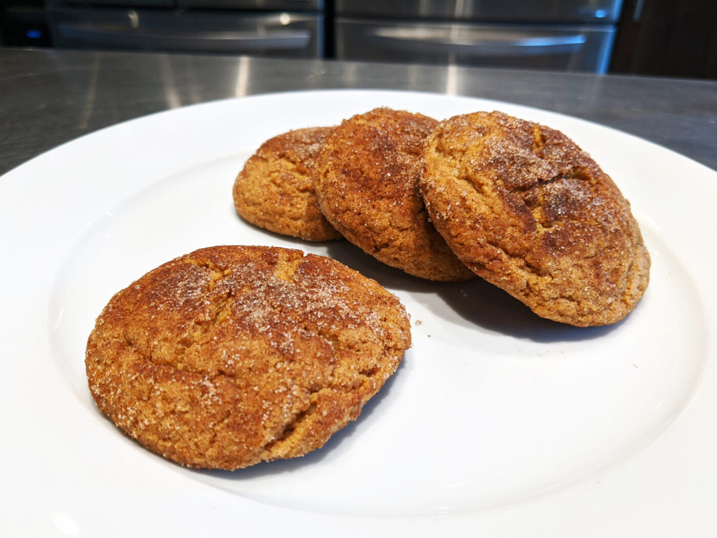 Gingersnap Cookies Four Gingersnap Cookies with cracked, sugar-crusted tops on a white plate.