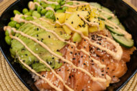 Poke Bowl with Salmon Poke Bowl with Salmon topped with salmon, avocado, mango, cucumber, edamame, sesame seeds and spicy mayo drizzle