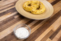 Garlic Dipping Sauce for Pretzels Small glass bowl of Garlic Dipping Sauce for Pretzels with herb flecks, beside a seeded pretzel.