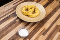 Garlic Dipping Sauce for Pretzels A small glass bowl of Garlic Dipping Sauce for Pretzels with visible chive flecks, set beside a seasoned pretzel.