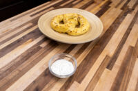 Garlic Dipping Sauce for Pretzels Small glass bowl of Garlic Dipping Sauce for Pretzels with herb flecks, next to a plate of pretzels on a wood table