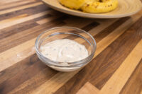 Garlic Dipping Sauce for Pretzels Glass bowl of Garlic Dipping Sauce for Pretzels, a creamy dip flecked with chives, on a wood table.