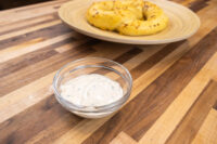 Garlic Dipping Sauce for Pretzels Glass bowl of Garlic Dipping Sauce for Pretzels with herb flecks, pretzels on wooden plate behind.