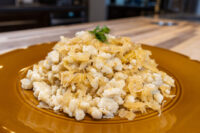 Halušky with Sauerkraut A mound of Halušky with Sauerkraut, white dumplings mixed with golden sauerkraut strands on a brown plate.