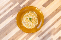 Halušky with Sauerkraut Halušky with Sauerkraut on a scalloped mustard plate, garnished with chopped herbs, set on striped wood.
