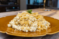 Halušky with Sauerkraut Mound of Halušky with Sauerkraut topped with a parsley sprig on a mustard-yellow scalloped plate.