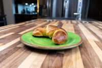 A golden Loupáčky Czech Poppy Seed Crescent curled on a green plate, its poppy-seed crust catching the light.