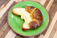 Sliced Loupáčky Czech Poppy Seed Crescent with poppy-seed crust and yellow crumb on a green plate.