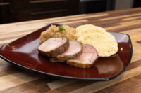 Sliced pork, sauerkraut, and dumpling rounds plated together for Pork-Sauerkraut-Dumpling (Vepřo-knedlo-zelo)