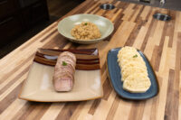 Sliced pork, sauerkraut, and dumpling rounds plated for Vepřo-knedlo-zelo on a wood counter.