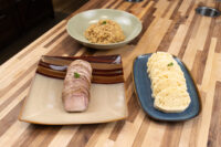 Sliced pork, a bowl of sauerkraut, and dumpling slices plated for Pork-Sauerkraut-Dumpling (Vepřo-knedlo-zelo).