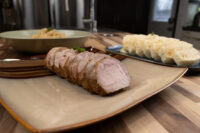 Sliced roast pork with a bowl of stewed sauerkraut and a platter of sliced dumplings, Vepřo-knedlo-zelo.