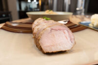 Sliced tied pork roast with a browned crust and pink interior, plated as the pork component of Pork-Sauerkraut-Dumpling (Vepřo-knedlo-zelo)