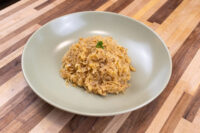 Sauerkraut (Kysane Zelí) A pale green bowl of Sauerkraut (Kysane Zelí), shredded and golden, topped with a small herb garnish on a wooden table.