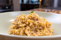 Sauerkraut (Kysane Zelí) White bowl heaped with shredded Sauerkraut (Kysane Zelí), browned edges, topped with a herb sprig.