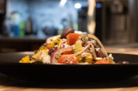 Greek Salad Greek Salad with diced tomatoes, red onion, olives, and feta piled on a dark plate.