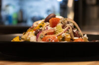 Greek Salad Greek Salad with tomato chunks, red onion, olives and feta piled on a dark plate
