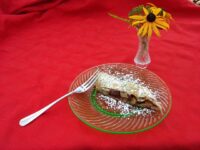 Apple Strudel Slice of Apple Strudel dusted with powdered sugar on a green-rimmed glass plate with a fork