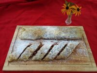 Apple Strudel Apple Strudel pastry roll, sliced and dusted with powdered sugar, on a wooden board.