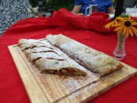 Apple Strudel Sliced Apple Strudel on a wooden board, dusted with powdered sugar, showing pale fruit filling.