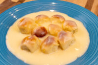 Nine golden buns in vanilla pudding sauce, Little Buns with Vanilla Pudding (Buchticky s Krémem), on blue plate