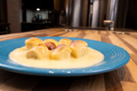 Little Buns with Vanilla Pudding (Buchticky s Krémem), golden buns coated in pale custard, served on a teal ridged plate atop a wooden counter