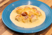 Nine golden Little Buns with Vanilla Pudding (Buchticky s Krémem) in custard on a blue plate