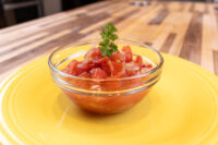 Czech Tomato Salad with Onion Glass bowl of Czech Tomato Salad with Onion, diced tomatoes and onion, parsley garnish, yellow plate.