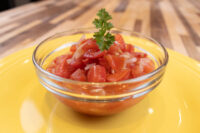 Czech Tomato Salad with Onion Glass bowl of Czech Tomato Salad with Onion, diced tomatoes and onion topped with parsley, on a yellow plate.